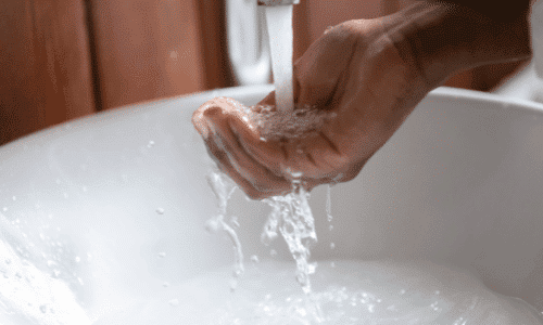 Woman washing hands under faucet