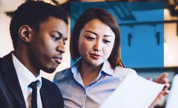 Black man and Asian woman looking at document together