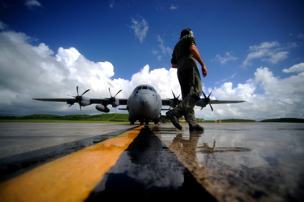 Us Air Force service man walking on runway with Airplane and blue sky in background