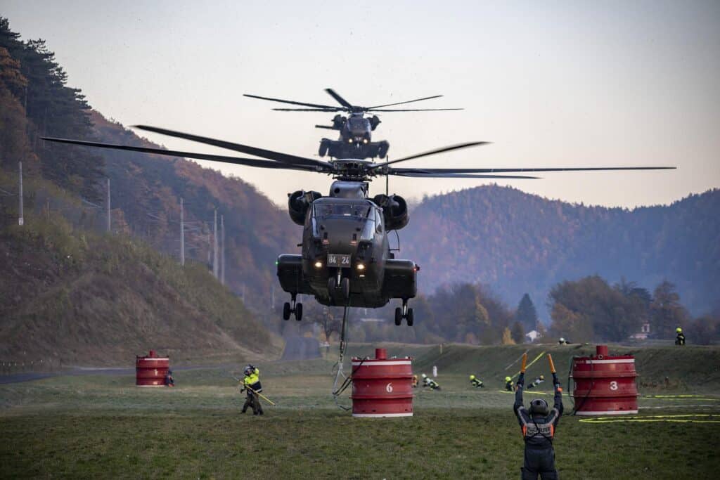 Helicopter in mid-air, lifting containers of water to help fight forest fires