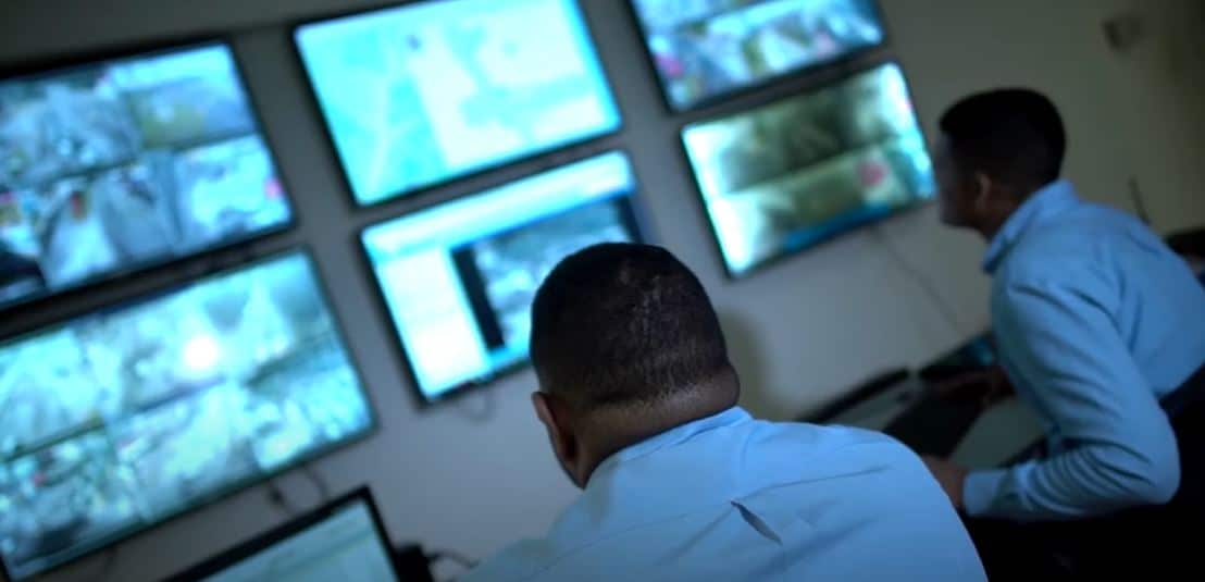 Two men looking at screens mounted on walls