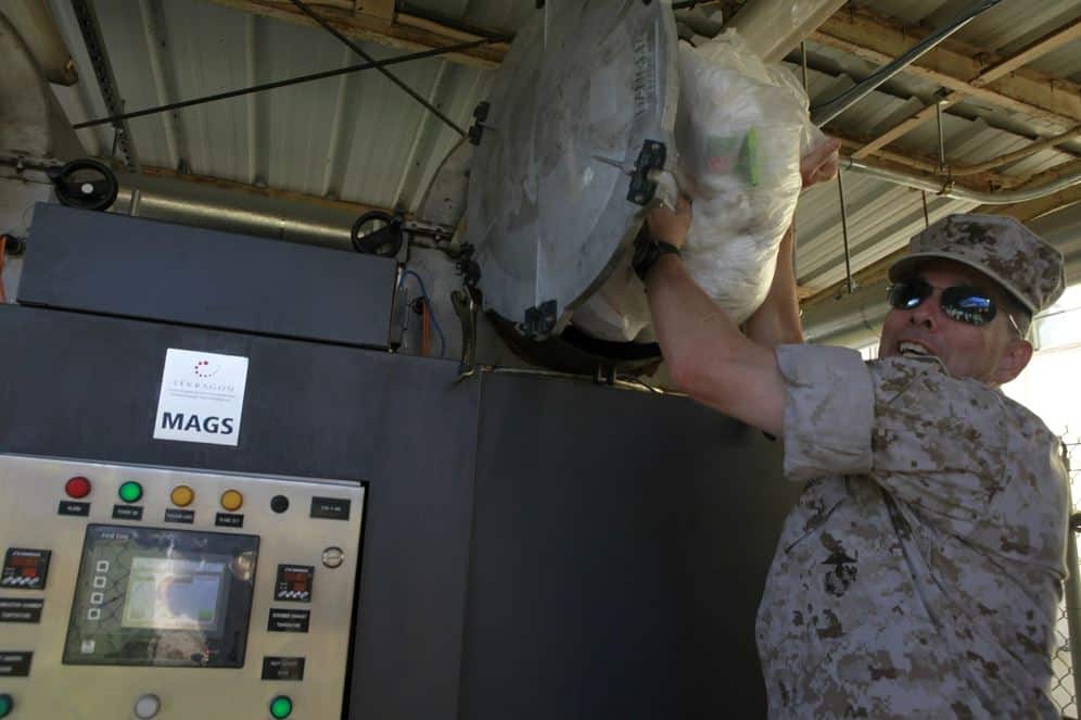 U.S. Marine Corps Maj. Gen. Peter J. Talleri, Commanding General, Marine Corps Installations Pacific, places garbage inside the Terragon Environmental Technologies Micro Auto Gasification System aboard Camp H. M. Smith, Hawaii, Oct. 18, 2011.