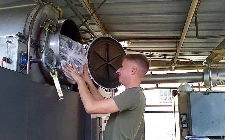 A Marine loads trash into a MAGS compact disposal system at Camp Smith, Hawaii.