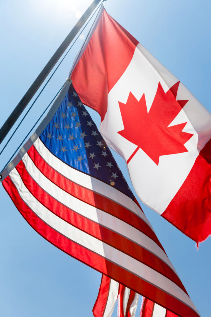 Photo of a Canadian and American flag flying together.